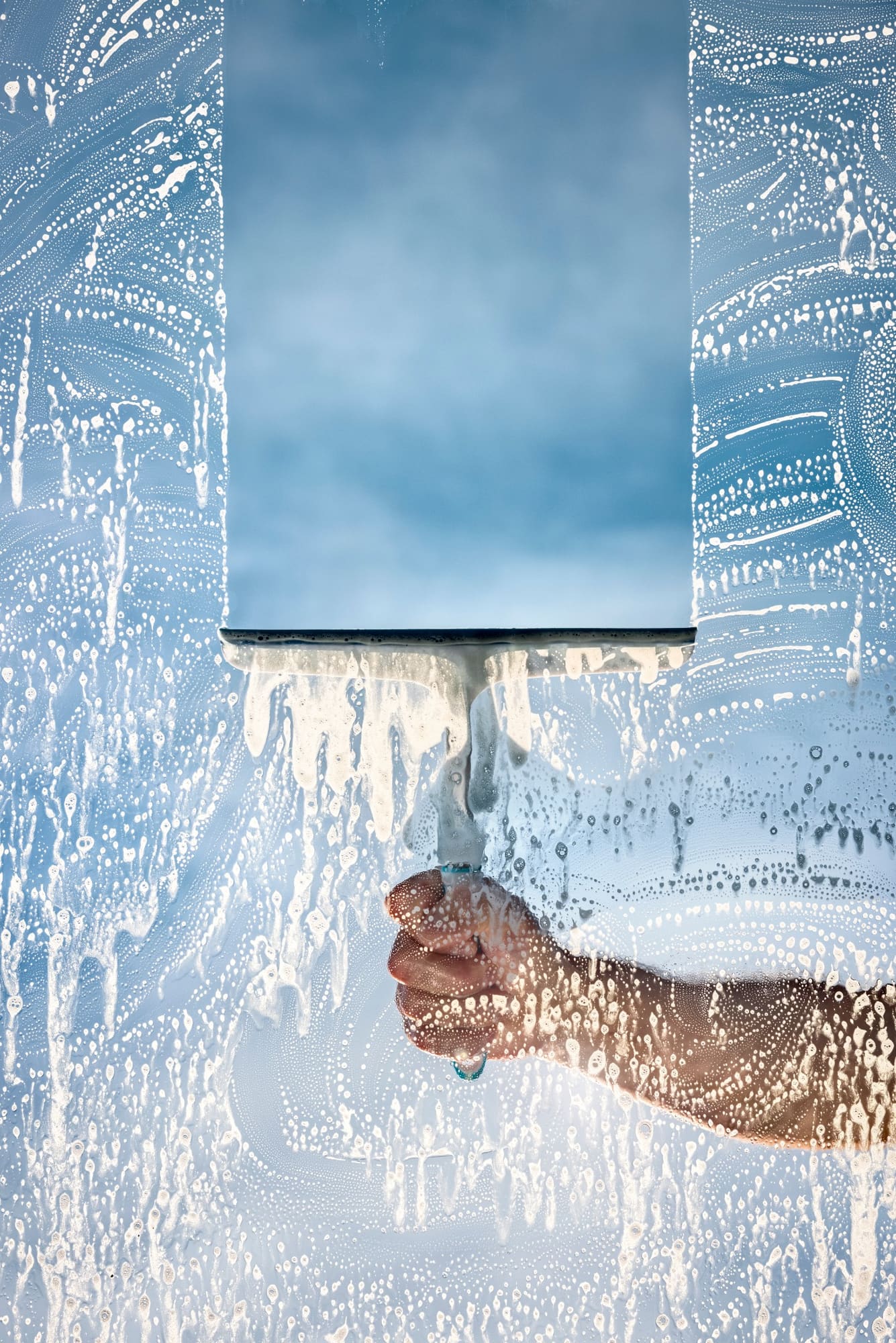Squeegee clearing soapy glass for a bright, clean view