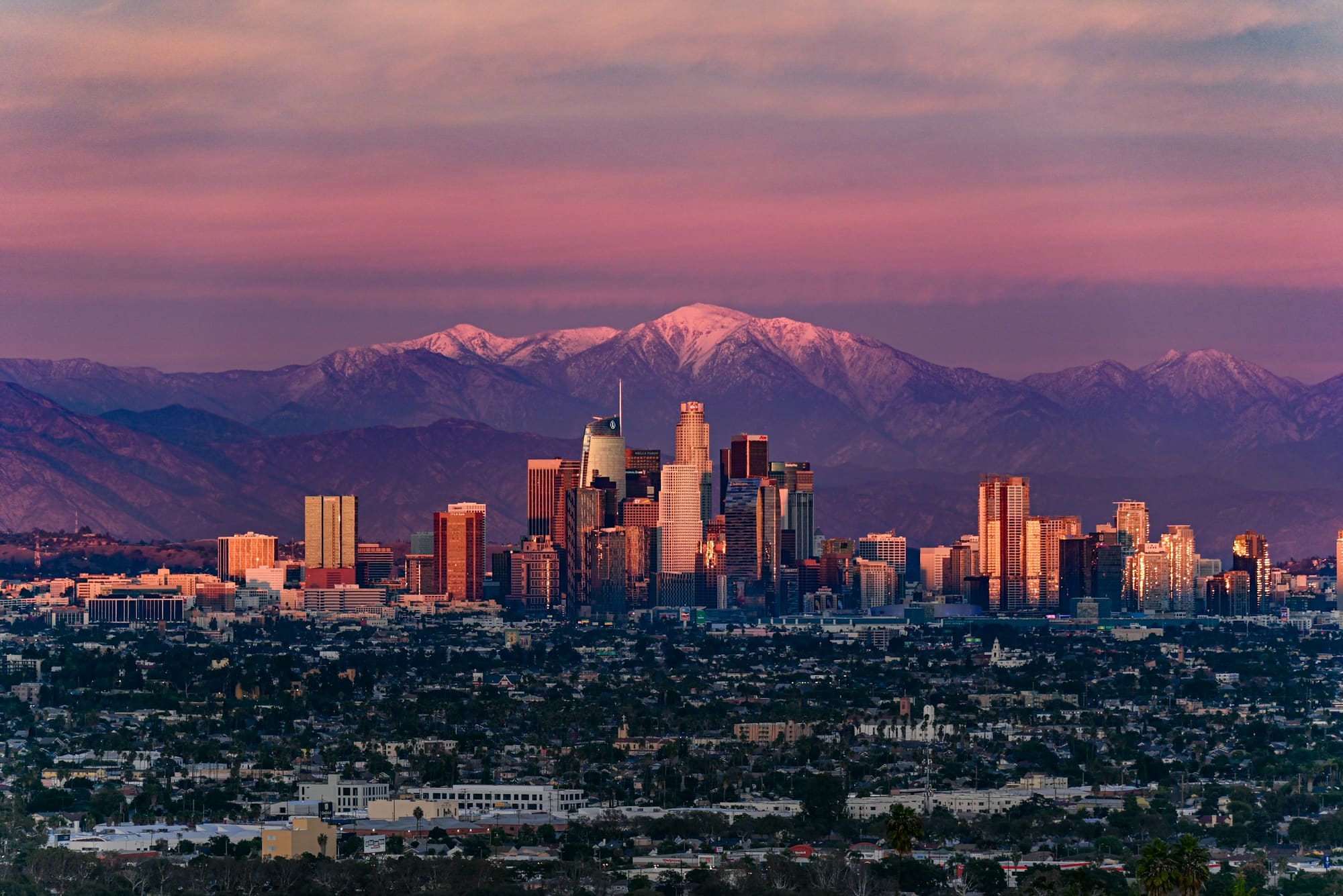 Downtown Los Angeles skyline at sunset against the San Gabriel Mountains